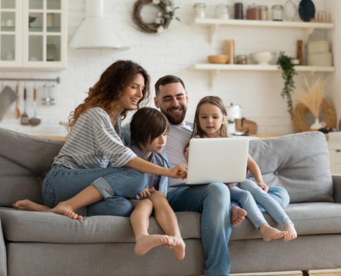 Happy family with kids sit on couch using laptop